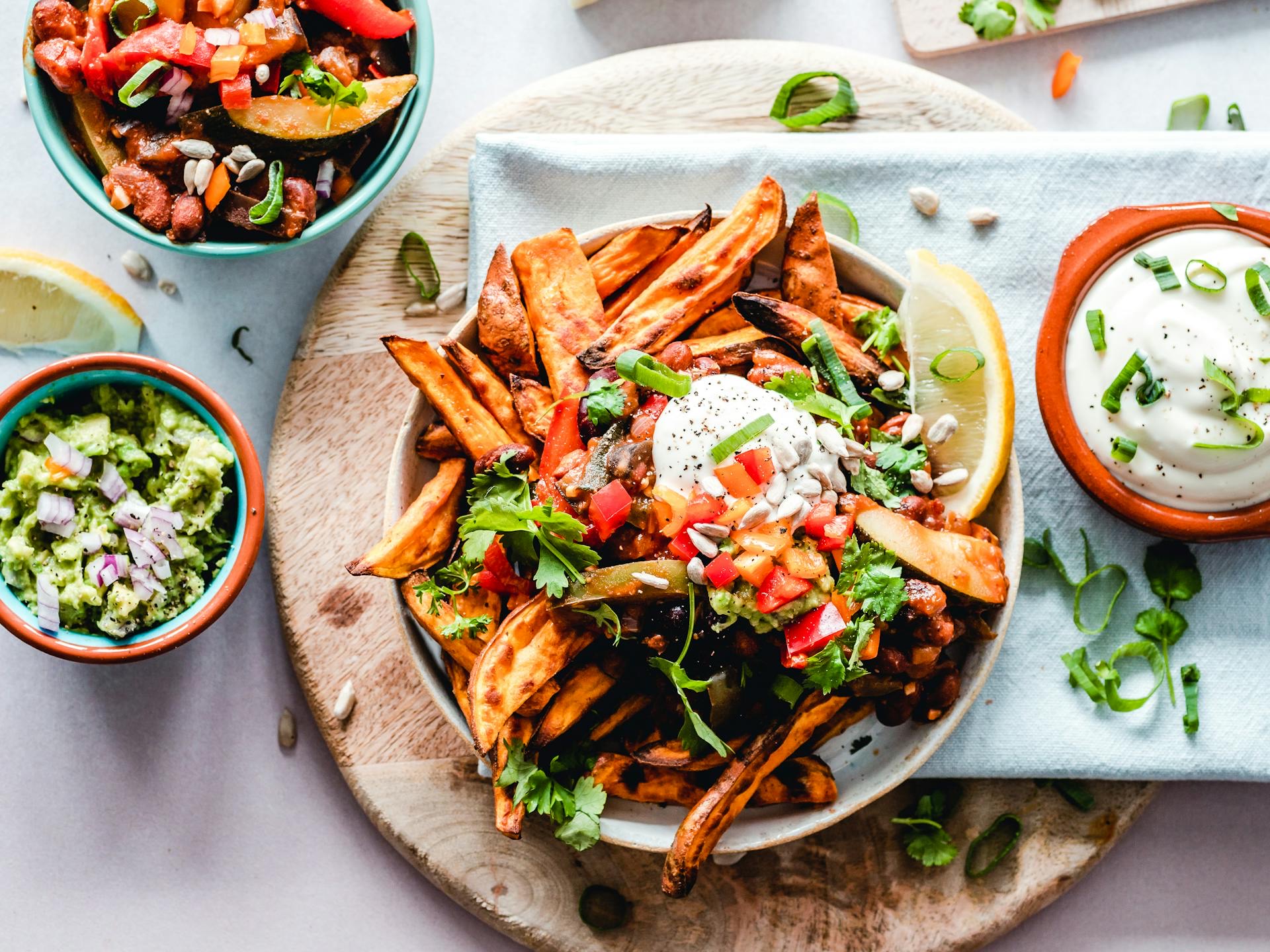 A colorful vegan dish with sweet potato fries, fresh guacamole, and toppings, showcasing the best vegan restaurants in Shoreditch.