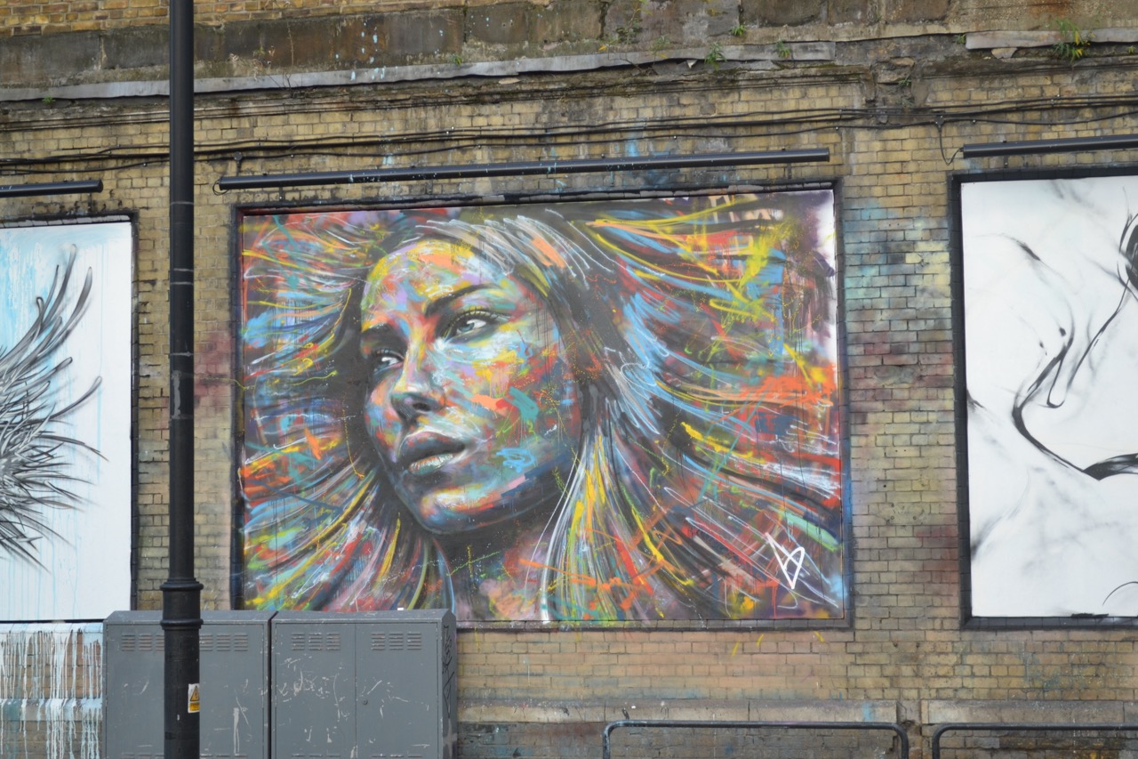 A vibrant mural of a woman’s face, bursting with color and creativity, showcasing iconic street art in Shoreditch.