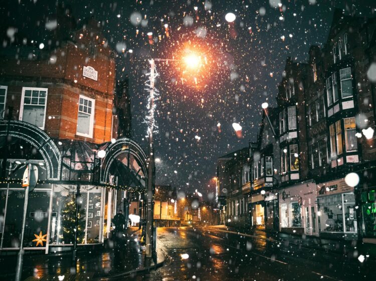 A magical snowfall illuminates a cozy Shoreditch street adorned with festive lights, capturing the spirit of Christmas.