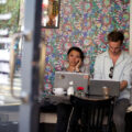 Two young professionals working on laptops in a trendy Shoreditch café, reflecting the energy of Shoreditch startups.