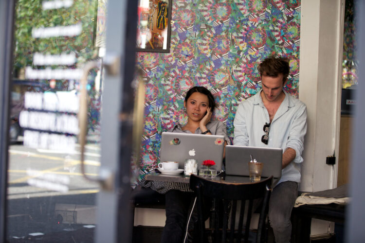 Two young professionals working on laptops in a trendy Shoreditch café, reflecting the energy of Shoreditch startups.