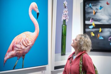 A visitor admires a striking flamingo artwork at the Fresh Art Fair, surrounded by vibrant and contemporary pieces.