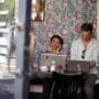 The Best Coworking Spaces in Shoreditch: Where Creativity and Innovation Thrive 1 Two young professionals working on laptops in a trendy Shoreditch café, reflecting the energy of Shoreditch startups.