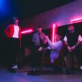 Indie rock band The K’s pose under neon lights, gearing up for The K’s UK tour, bringing their electrifying sound to London.