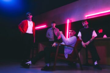 Indie rock band The K’s pose under neon lights, gearing up for The K’s UK tour, bringing their electrifying sound to London.