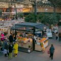 Bustling scene at Old Spitalfields Market in London, featuring artisan stalls, fresh produce, and vibrant shopping spots.