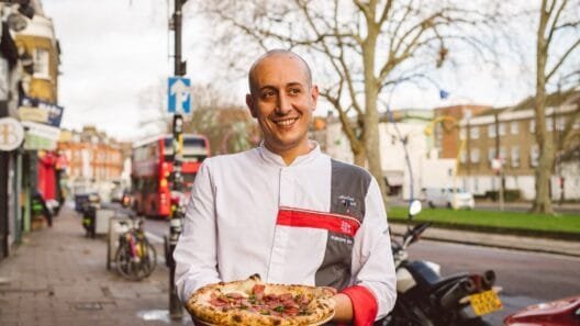 Andrea Asciuti holding Neapolitan pizza in front of 081 Pizzeria