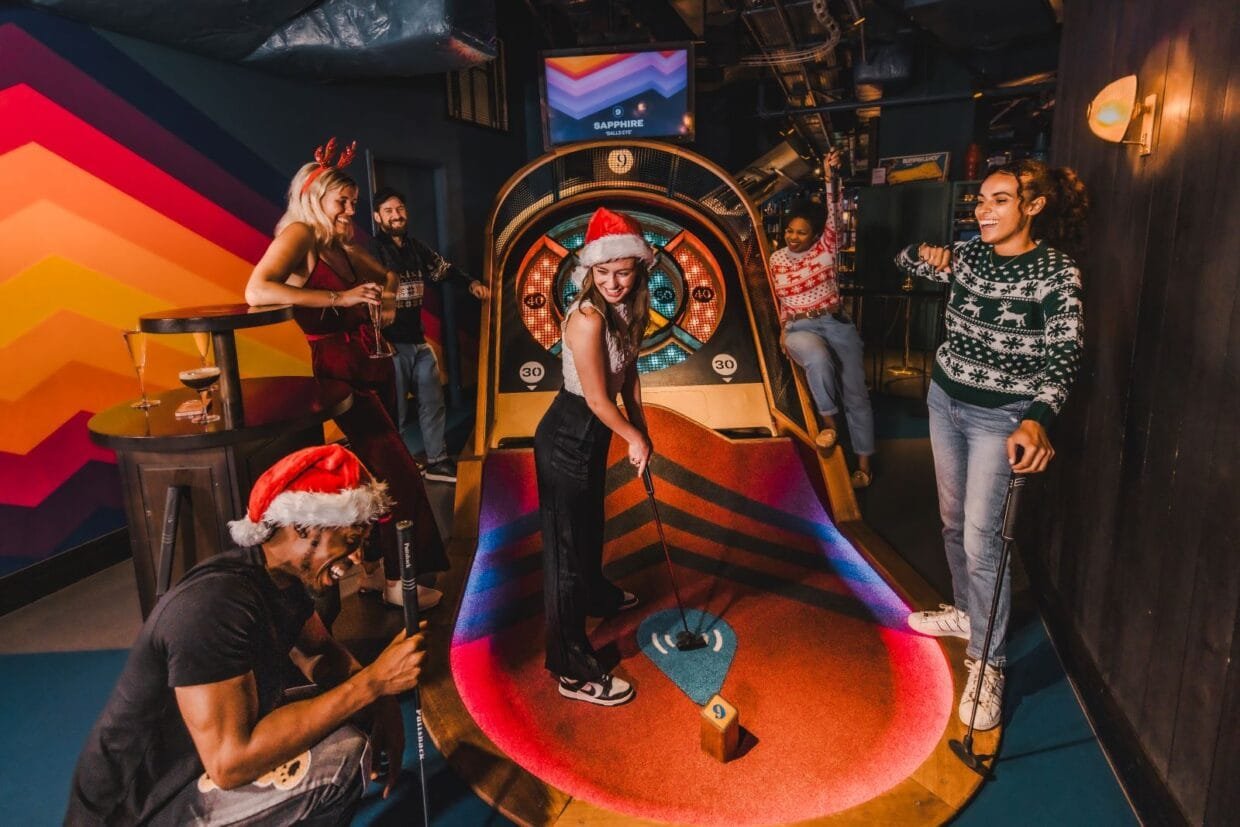 Inside the New Puttshack Festive Menu Taking Over London This Christmas 6 A high-tech mini golf course at Puttshack featuring vibrant lights and holiday décor, part of the experience offered with the Puttshack festive menu.