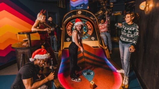 A high-tech mini golf course at Puttshack featuring vibrant lights and holiday décor, part of the experience offered with the Puttshack festive menu.