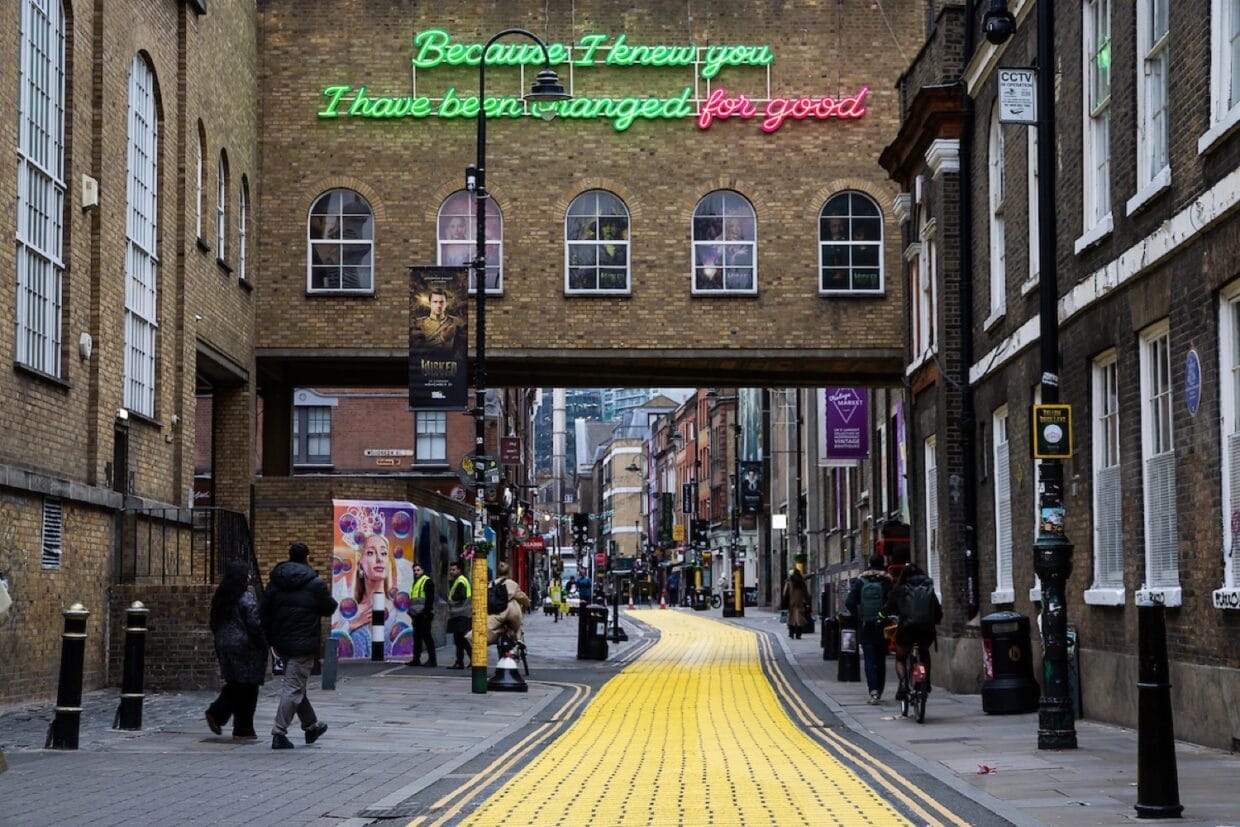 Neon lyric installation above the Truman Brewery Bridge illuminating the Wicked Yellow Brick Lane walking trail.