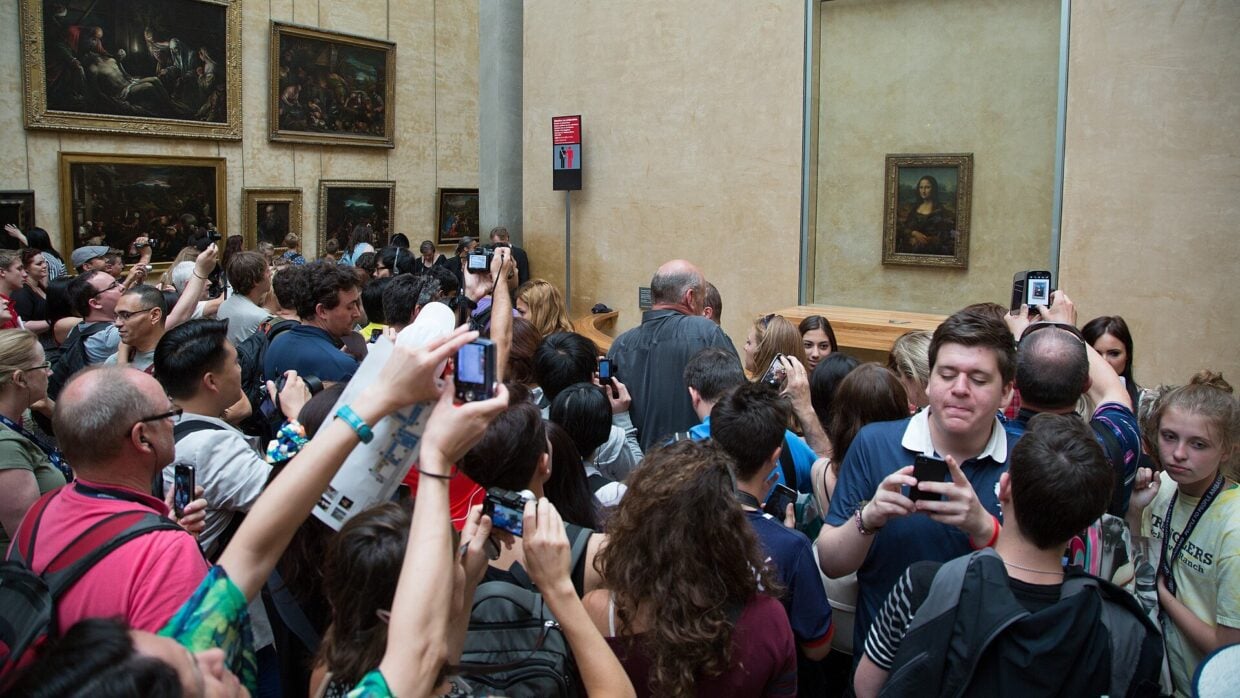 Crowd of visitors photographing the Mona Lisa at the Louvre